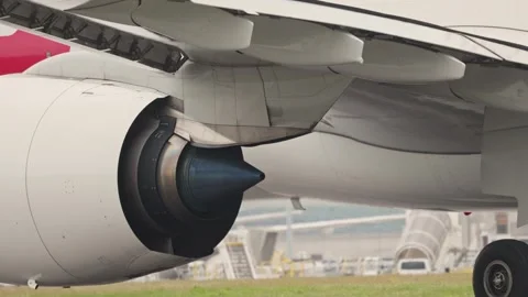 Large passenger airplane engine and wing detail on airport tarmac Stock Footage 306380788