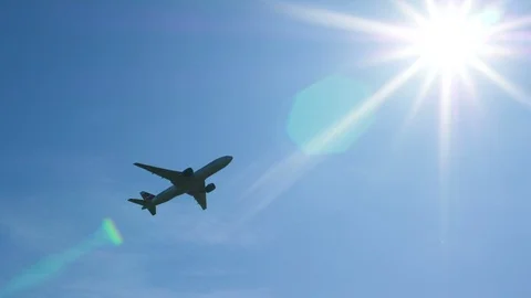 Large passenger plane gaining altitude after takeoff in front of the bright sun Stock Footage 115489616