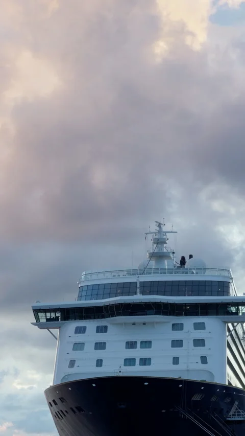Large passenger ship bow rising beneath dramatic pastel clouds on calm open Stock Footage 345764797