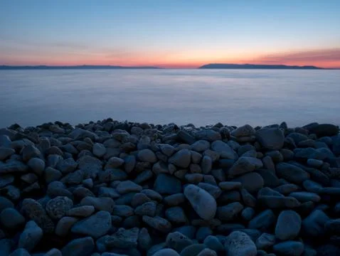 Large pebbles on beach at sunset Stock Photos