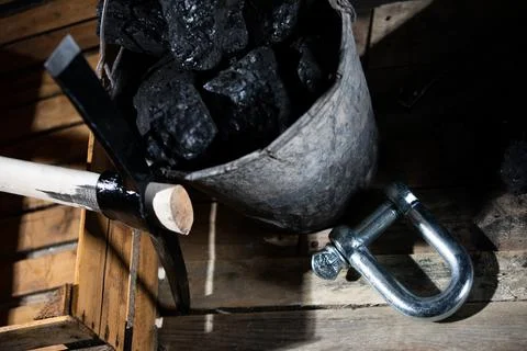 Large pickaxe with wooden handle on black background with lumps of black coal Stock-Fotos