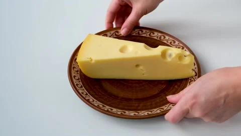 A large piece of cheese lies on a ceramic plate Stock Footage 168528896