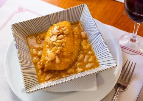 Large piece of lean cod fillet stewed in bean gravy Stock Photos