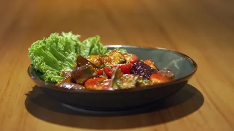 On a large piece of lettuce leaf there is a salad with fried eggplants, cherry Stock Footage 256143284