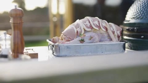 A large piece of meat is sitting on a silver tray next to a grill Stock Footage 295369444