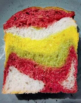 A large piece of multi-colored bread lies on a plate. Photographed close up Stock Photos