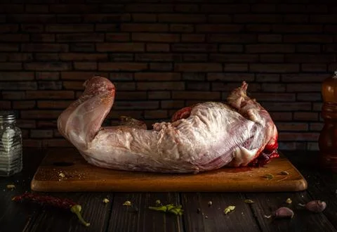 A large piece of raw rabbit meat is placed on a wooden cutting board. Salt an Stock Photos