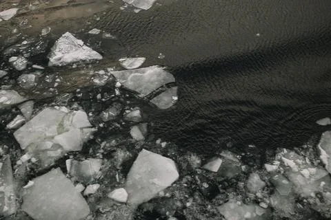 Large pieces of ice float in a dark water body during winter season Stock Photos