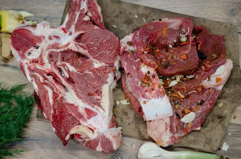 Large pieces of raw beef on the bone with spices and garlic on a cutting boar Stock Photos