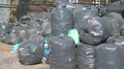 A large pile of black garbage bags stacked in an outdoor area in 4k slow mo.. Video stock 282879280
