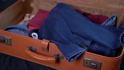 Large Pile of Clothes Thrown in an Open Old Brown Suitcase. 4K. Close up. 動画素材 153890964