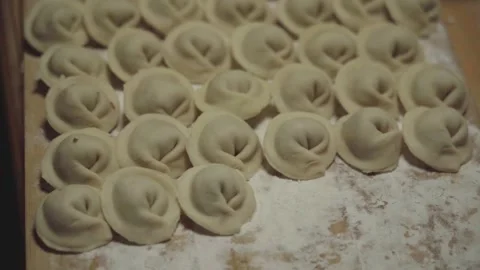 A large pile of dumplings are being made on a wooden table Stock Footage 293501544