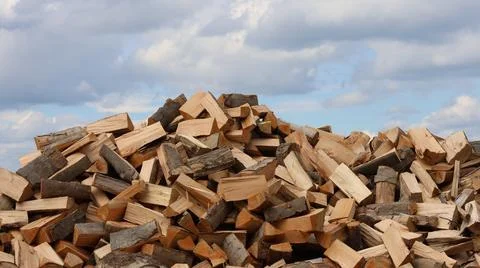 A large pile of freshly split firewood beneath a cloudy sky, Stock Photos