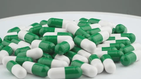 A large pile of green and white capsules is scattered on a white surface Stock-Footage 341033866