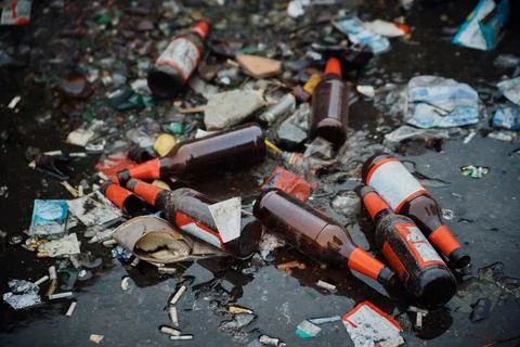 A large pile of household garbage on the sidewalk. Used glass bottles and pap Stock Photos