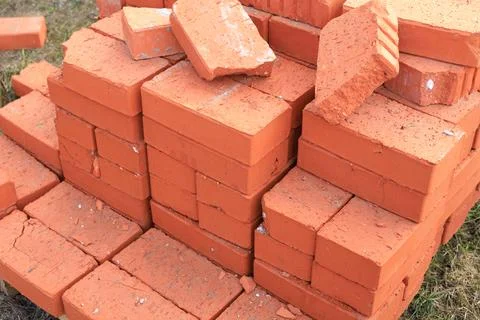Large pile of red ceramic bricks stacked on a wooden pallet at a construction Stockfoto's