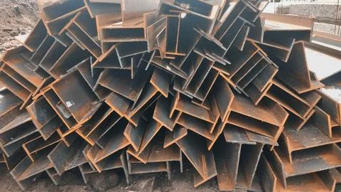 Large pile of rusty structural H-beam steel profiles at a construction site. Stock Photos