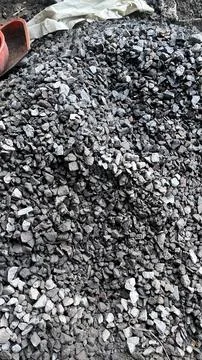 A large pile of small gray and black crushed stones fills the frame with a re Foto stock