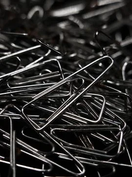A large pile of triangular shaped shiny silver paper clips Stock Photos