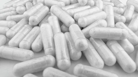A large pile of white capsules is scattered in a random arrangement, creating a 스톡 동영상 341033935
