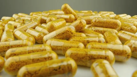 A large pile of yellow capsules filled with powdered supplement is scattered Stock Footage 341038277