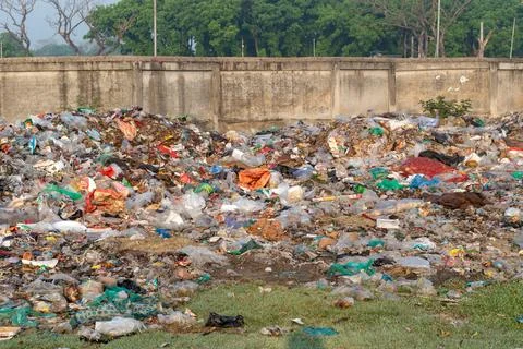 Large piles of mixed plastic trash and waste scattered across an open field.. Stock-Fotos