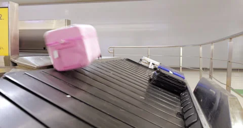 Large pink suitcase rolls-slide down to luggage conveyor, airport arrival scene Stock Footage 292920389