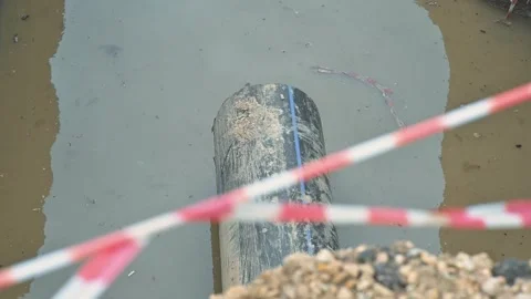 A large pipe lies submerged below the water's surface, with warning tape visible 動画素材 344675891