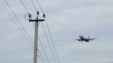 A large plane is landing against the background of industrial wires  Stock Footage 158023069