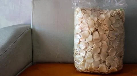 A large plastic bag filled with round, thin, beige-colored crackers is plac.. Stock Photos