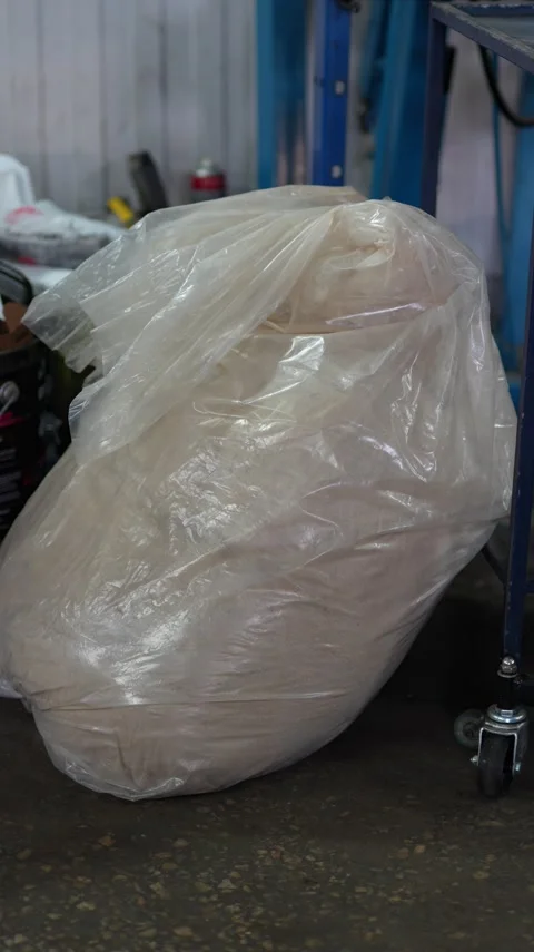 Large plastic bag filled with sawdust or powder in workshop. Stock Footage 343889556