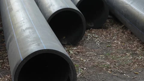 Large plastic black pipes lie on the ground outside. Close-up view from the end Stock-Footage 287416416