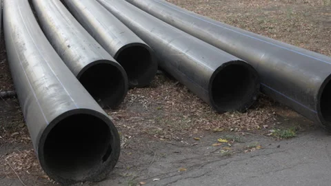 Large plastic black pipes lie on the ground outside Stock Footage 288436564