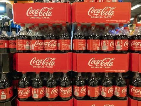 Large plastic bottles of Coca Cola soft in boxes in a supermarket. Stock Photos