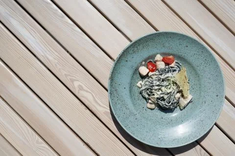 Large plate with a small portion of pasta with fish on a wooden table Stock-Fotos