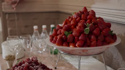 A large plate of strawberries is on the buffet table. Nearby are glasses, water 스톡 동영상 131585868