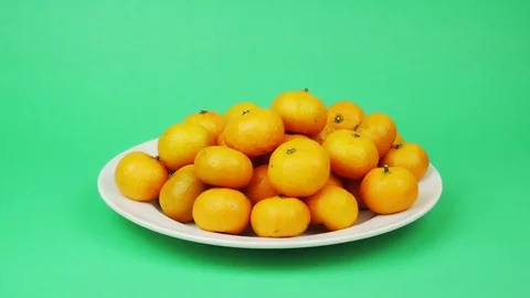 Large plate with tangerines on a green background Stock Footage 121874198