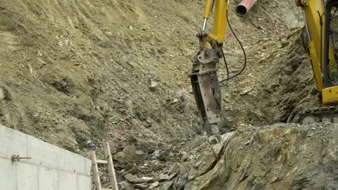 A large pneumatic hammer on an excavator breaks rocks in a quarry, on a construc Vídeos de archivo 106579516