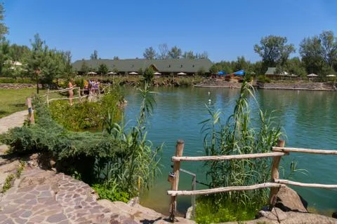 A large pond with paths lined with stone around it with walking people agains Stock Photos