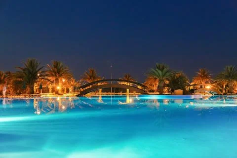 A large pool with a bridge over it and palm trees in the background Foto stock