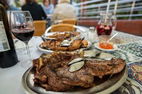 Large portion of beef, chicken, and pork platters with bottle of red wine and Stock Photos