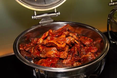 Large portion of pork ribs inside a restaurant buffet tray. Stock Photos