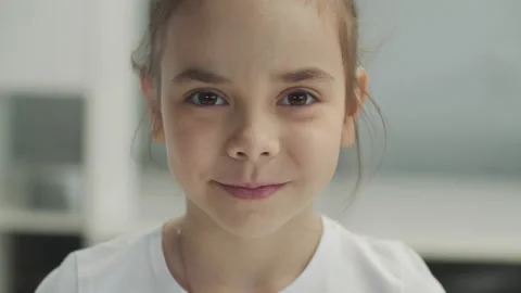 Large portrait of a small brown-eyed smiling girl in a white T-shirt Stock Footage 151493367