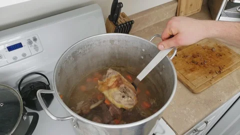 Large pot of simmering Turkey gizzards and previously roasted Duck being stirred Stock Footage 104249030