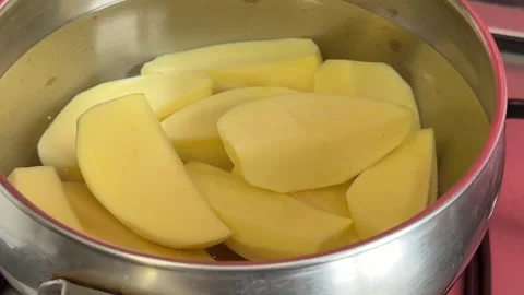 Large potato pieces soaking in water inside cooking pot with natural starch Stock Footage 345720634