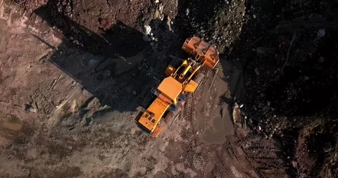 Large powerful yellow mining wheel operating loader lifts brown dirt on Stock Footage 139689356