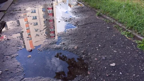 A large puddle on a cracked asphalt path reflects  Видео 339096951