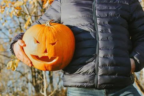 A large pumpkin in the hands of a man, close-up. Concept Halloween Party 写真素材