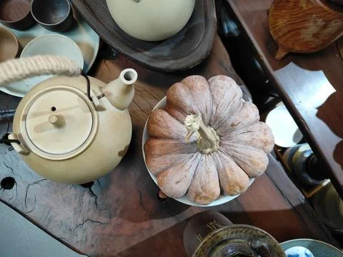 A large pumpkin is placed on the table, and there's an ancient Chinese teap.. Stock Photos