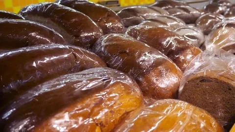 Large quantities of baked goods (loaf or bread) in transparent cellophane bags. Stock Footage 307638073